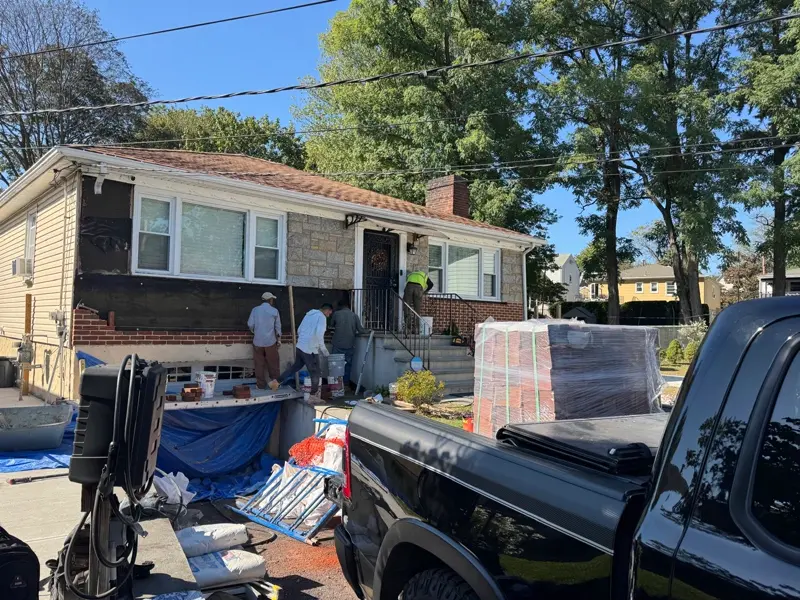 Workers repairing brick and siding on a residential home in Nassau County