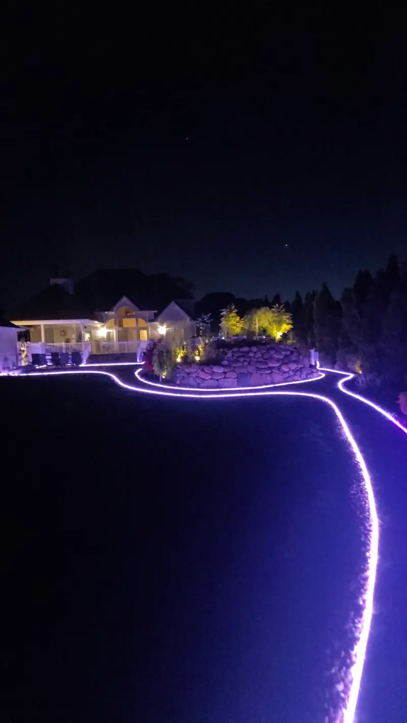 Nighttime view of property with custom LED landscape lighting along walkways and garden borders
