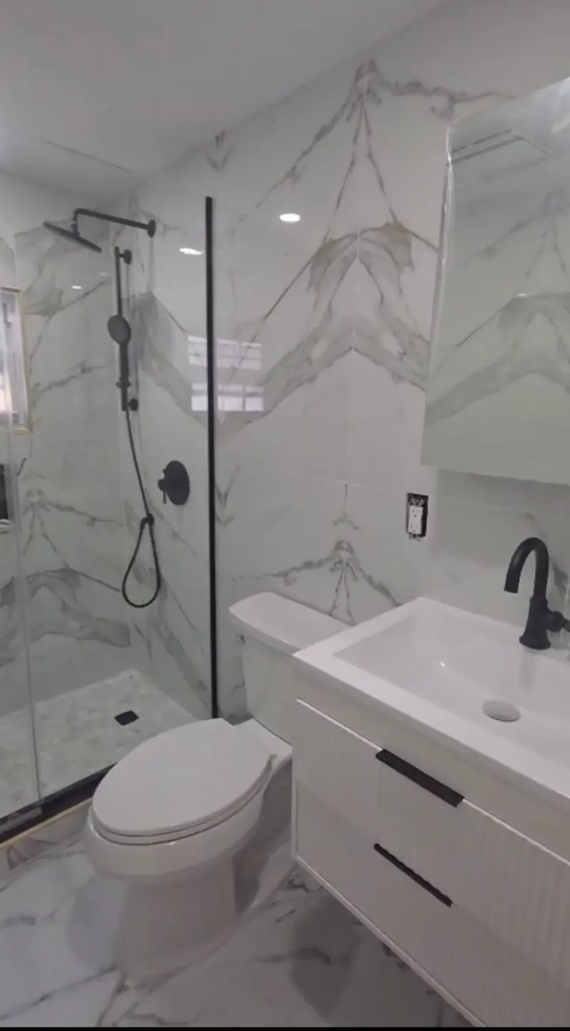 Modern bathroom remodel with marble tile walls, walk-in shower, and floating vanity
